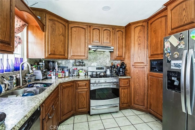 kitchen featuring light tile patterned floors, brown cabinetry, stainless steel appliances, under cabinet range hood, and a sink