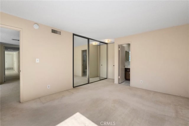 unfurnished bedroom with carpet floors, visible vents, and ensuite bathroom