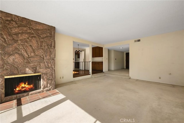 unfurnished living room with carpet floors, an inviting chandelier, a fireplace, and visible vents