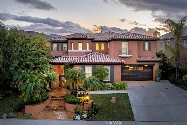 mediterranean / spanish-style home with stucco siding, a tile roof, concrete driveway, a garage, and a chimney