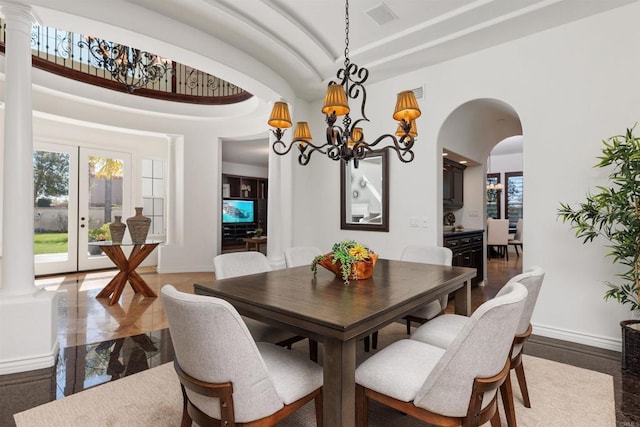 dining area with arched walkways, visible vents, baseboards, decorative columns, and an inviting chandelier