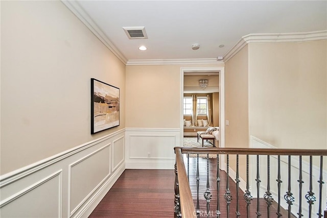 corridor with dark wood-style floors, recessed lighting, visible vents, ornamental molding, and an upstairs landing