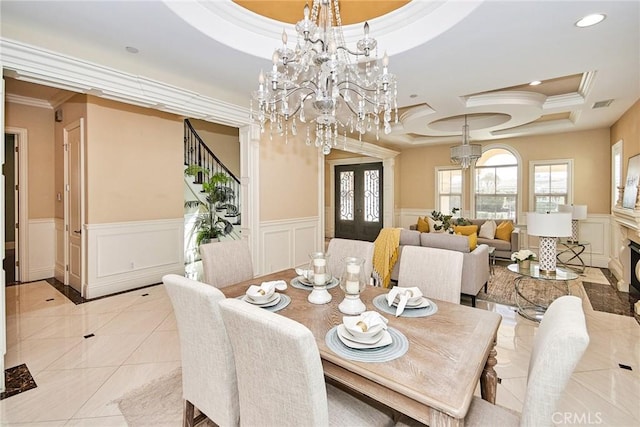 dining area featuring crown molding, a raised ceiling, visible vents, a chandelier, and stairs