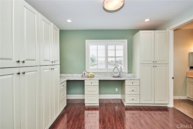 unfurnished office with baseboards, dark wood-type flooring, built in desk, and recessed lighting