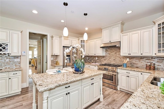 kitchen featuring light wood-style flooring, recessed lighting, under cabinet range hood, stainless steel appliances, and a center island