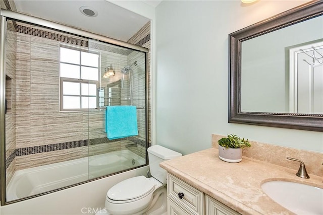 bathroom with toilet, combined bath / shower with glass door, and vanity