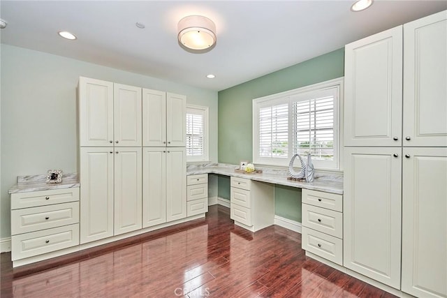 unfurnished office with dark wood-style flooring, built in desk, and recessed lighting