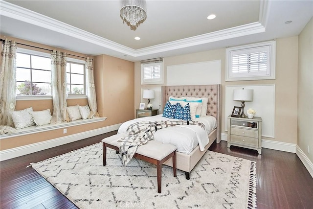 bedroom featuring multiple windows, baseboards, a raised ceiling, and dark wood finished floors