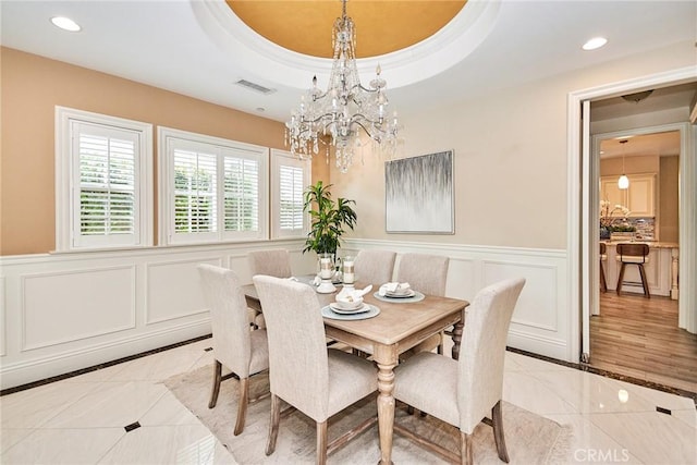 dining area featuring recessed lighting, a wainscoted wall, visible vents, a tray ceiling, and an inviting chandelier