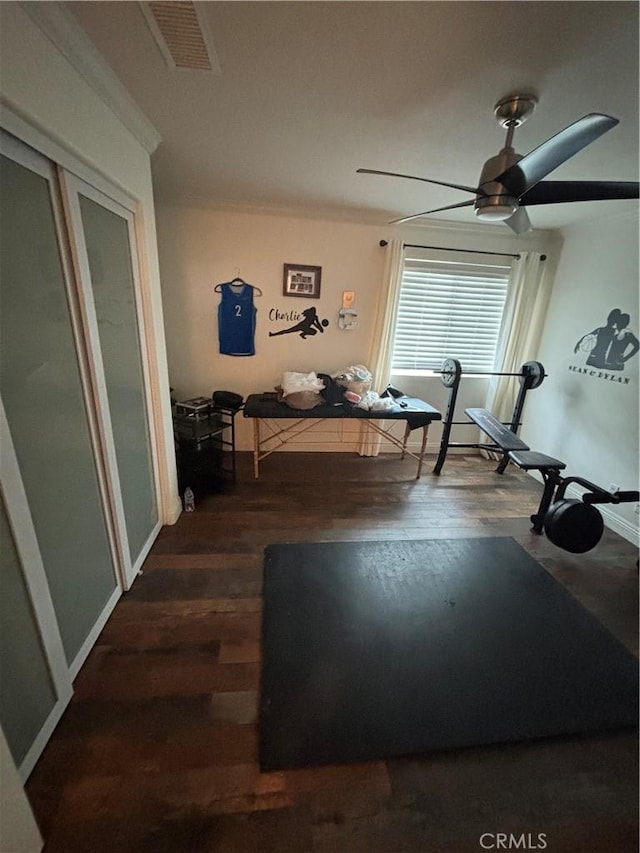 workout area featuring a ceiling fan, visible vents, ornamental molding, and wood finished floors