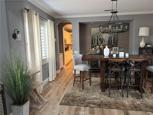 bar featuring visible vents, arched walkways, wood finished floors, and ornamental molding