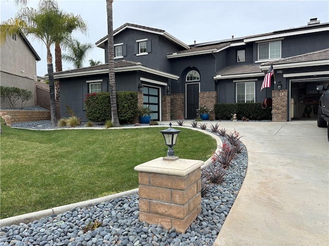 view of front of home featuring driveway, a front lawn, brick siding, and stucco siding