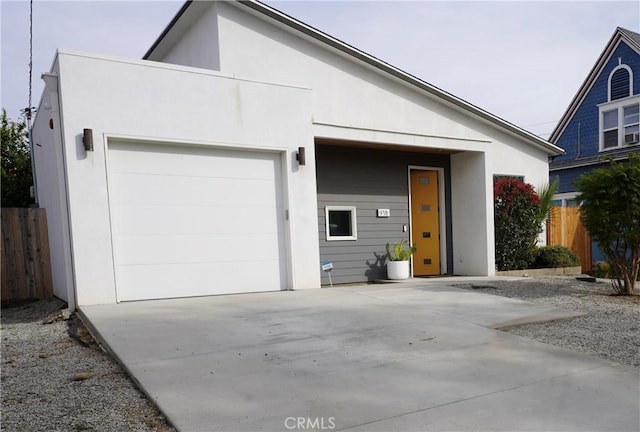 view of front of property featuring fence, concrete driveway, and stucco siding