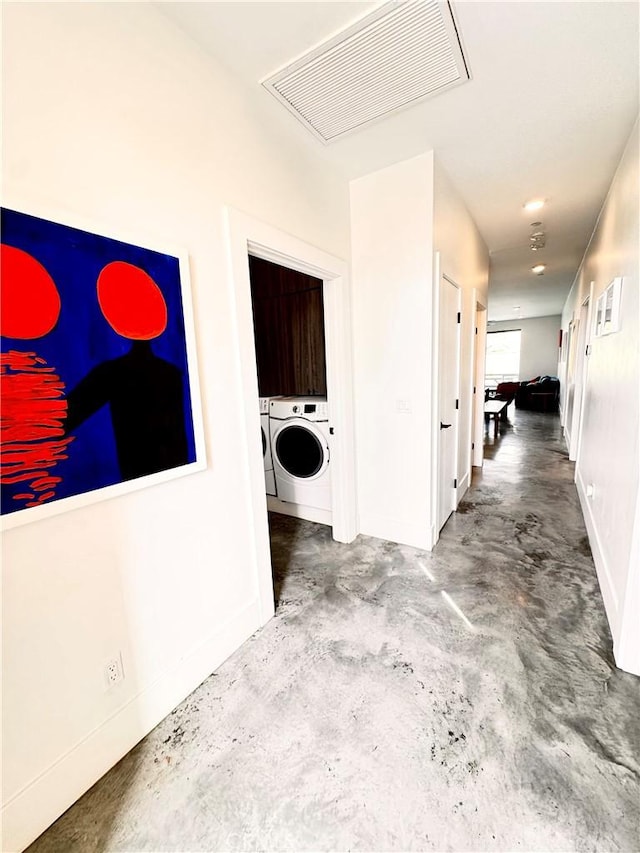 hallway featuring baseboards, concrete floors, visible vents, and separate washer and dryer