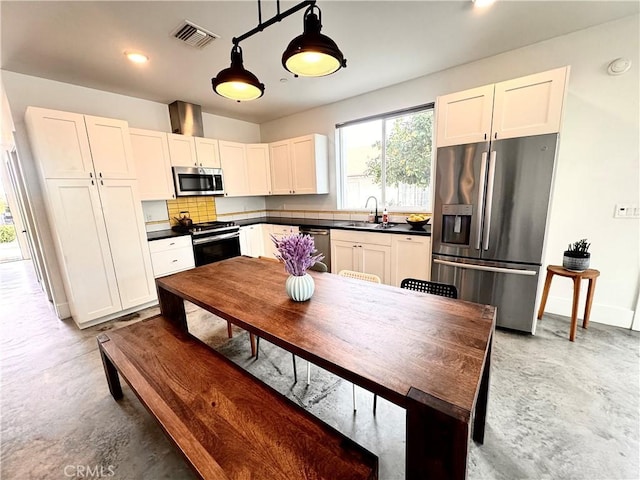 kitchen with appliances with stainless steel finishes, dark countertops, a sink, and visible vents