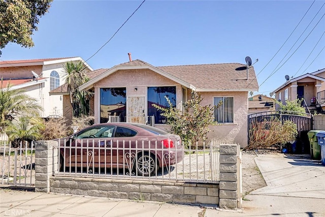 bungalow-style home featuring a fenced front yard, a gate, and stucco siding