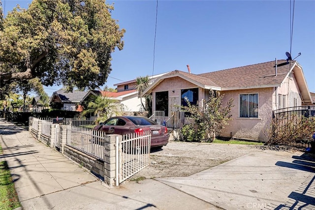 bungalow-style house featuring a fenced front yard and stucco siding