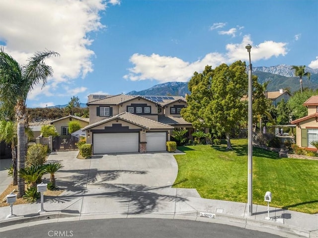 traditional-style house featuring concrete driveway, a front yard, a mountain view, a garage, and a tiled roof