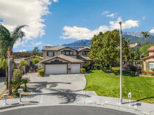 traditional-style home featuring an attached garage, a front lawn, a mountain view, and driveway