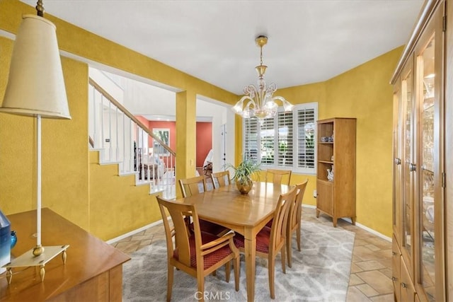 dining room with stone tile flooring, stairway, baseboards, and an inviting chandelier