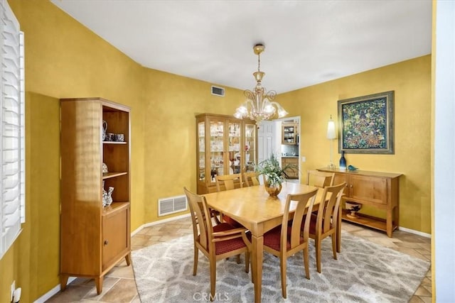 dining area featuring a chandelier, baseboards, visible vents, and stone tile floors