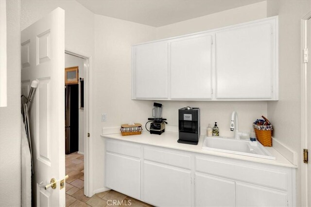 kitchen featuring light countertops, a sink, and white cabinetry