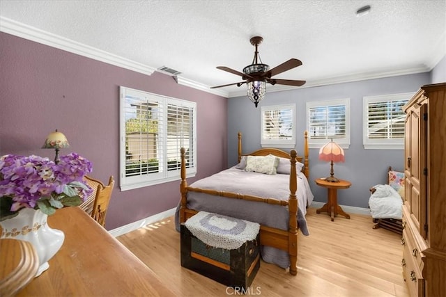 bedroom featuring multiple windows, a textured ceiling, light wood-style flooring, and ornamental molding