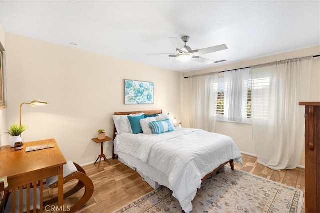 bedroom with light wood finished floors, baseboards, ceiling fan, and visible vents