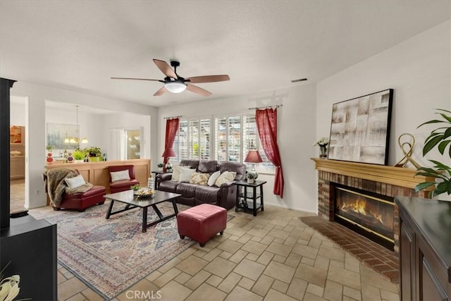 living area featuring a fireplace, visible vents, and ceiling fan with notable chandelier