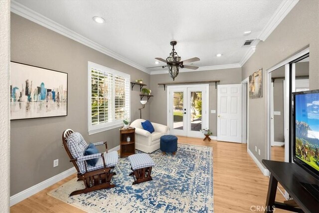 living area with light wood-style floors, visible vents, crown molding, and french doors