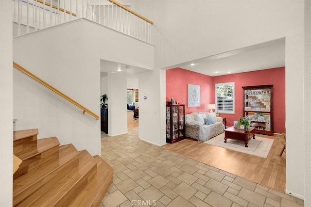 living room featuring stairway, wood finished floors, a towering ceiling, and baseboards