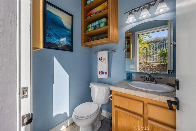 half bath with vanity, toilet, and baseboards