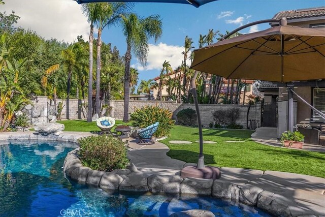 exterior space featuring a yard, a patio area, fence, and a fenced in pool