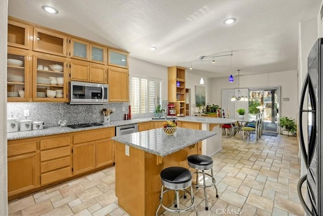 kitchen with a breakfast bar, tasteful backsplash, stone finish floor, a peninsula, and black appliances