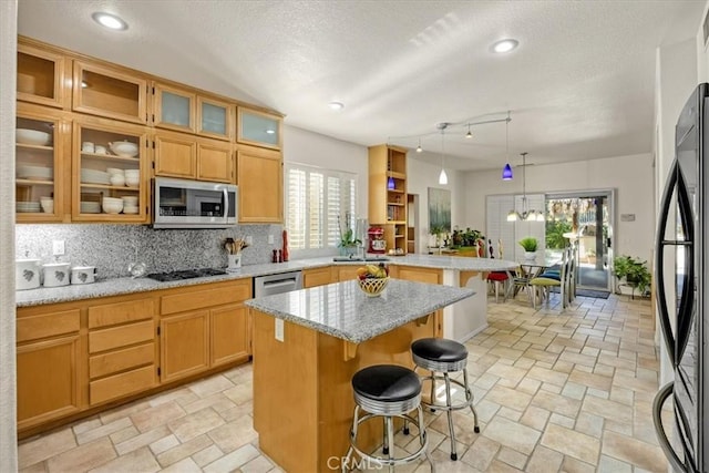kitchen with stainless steel microwave, a peninsula, fridge, a breakfast bar, and a textured ceiling