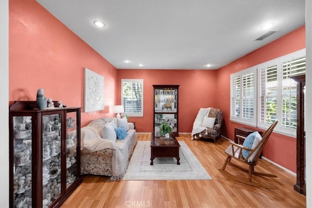 living area with recessed lighting, visible vents, baseboards, and wood finished floors