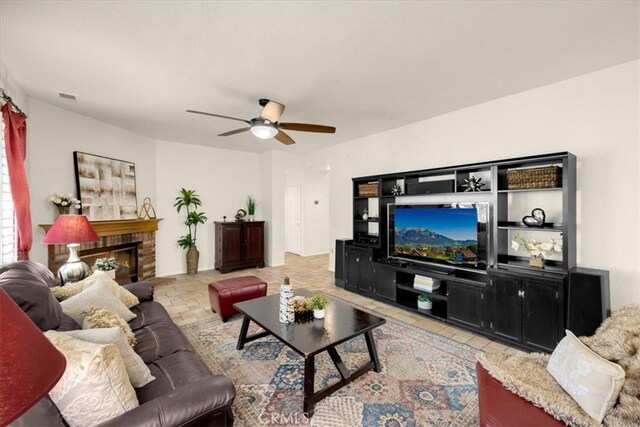 living area featuring a brick fireplace, visible vents, and a ceiling fan