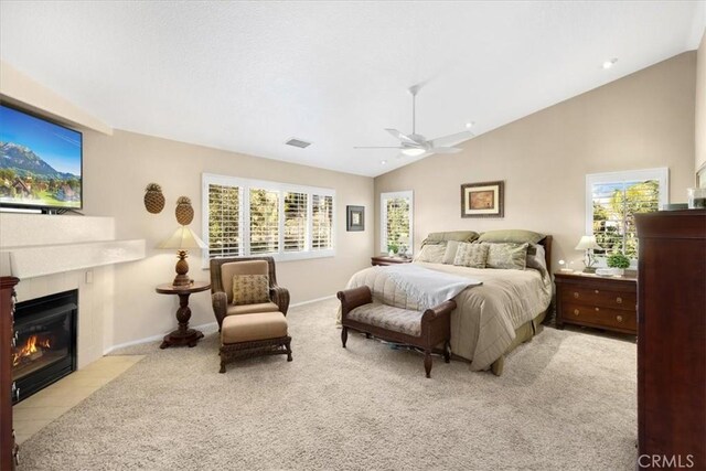 carpeted bedroom featuring baseboards, visible vents, a ceiling fan, lofted ceiling, and a fireplace with flush hearth