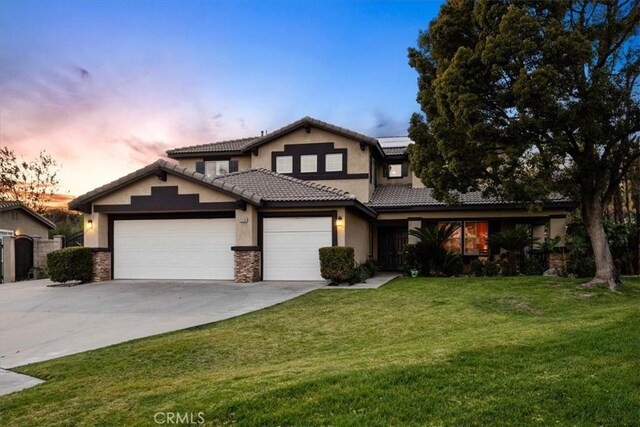 view of front of home featuring an attached garage, a yard, stone siding, driveway, and stucco siding