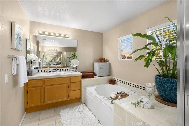 bathroom with a garden tub, vanity, and tile patterned floors