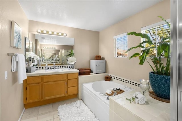 bathroom with a garden tub, baseboards, tile patterned flooring, and vanity