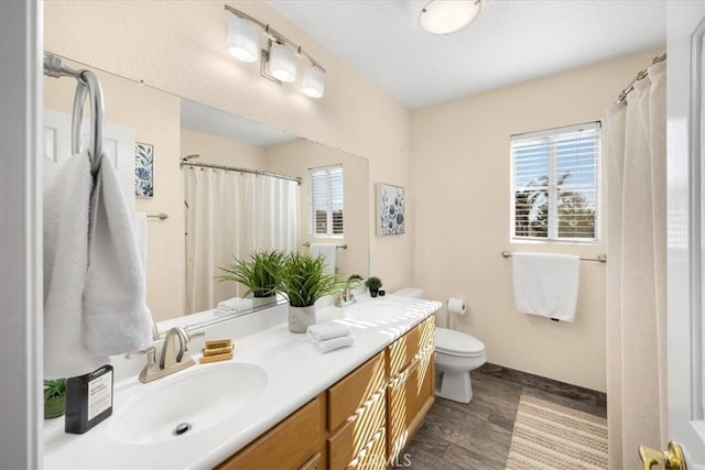 bathroom featuring double vanity, toilet, wood finished floors, and a sink