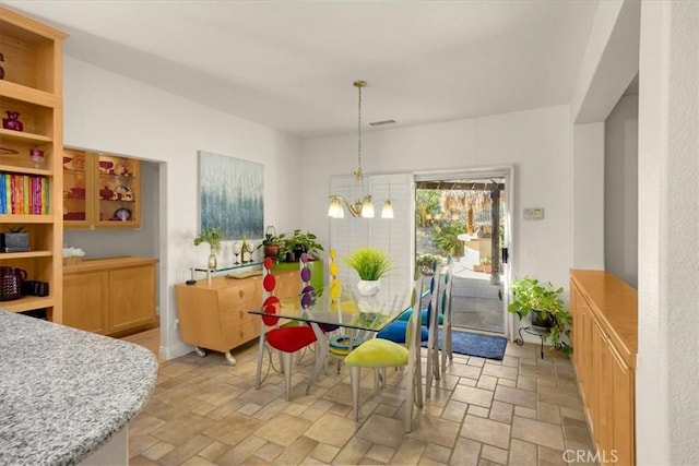 dining area with an inviting chandelier and stone tile floors