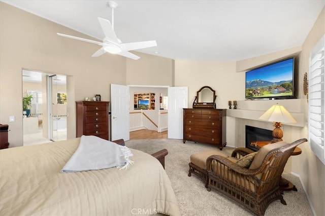 bedroom with high vaulted ceiling, a glass covered fireplace, carpet flooring, and ensuite bath