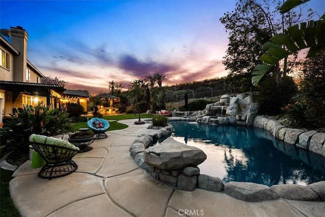 outdoor pool with fence, a patio, and a fire pit