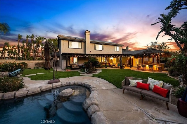 back of house featuring outdoor dry bar, a patio area, a lawn, and a fenced backyard