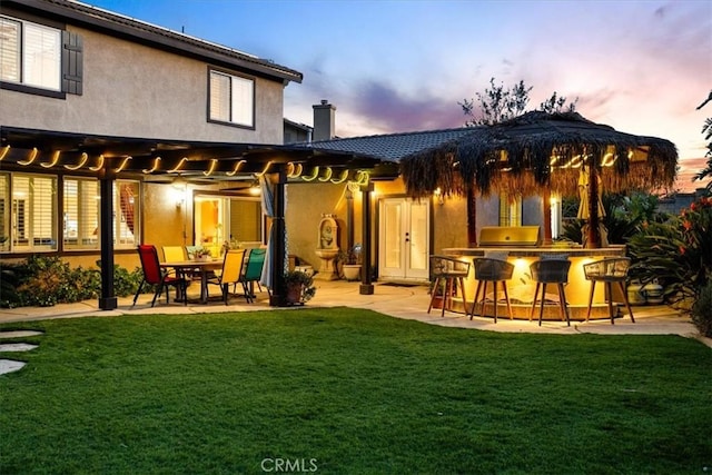rear view of house featuring a yard, a patio area, outdoor dry bar, and a chimney