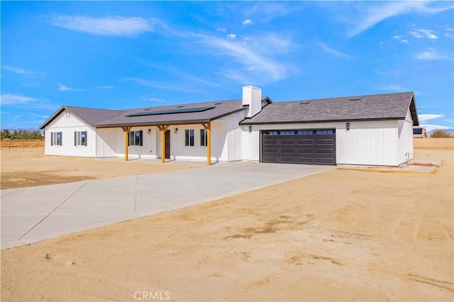 modern farmhouse with driveway, an attached garage, and roof mounted solar panels