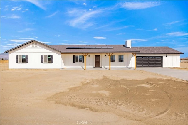 view of front of property with an attached garage, roof mounted solar panels, and concrete driveway