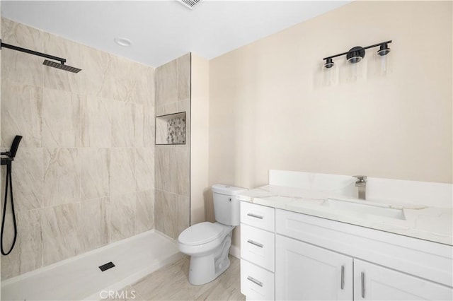 full bath with a tile shower, vanity, and toilet